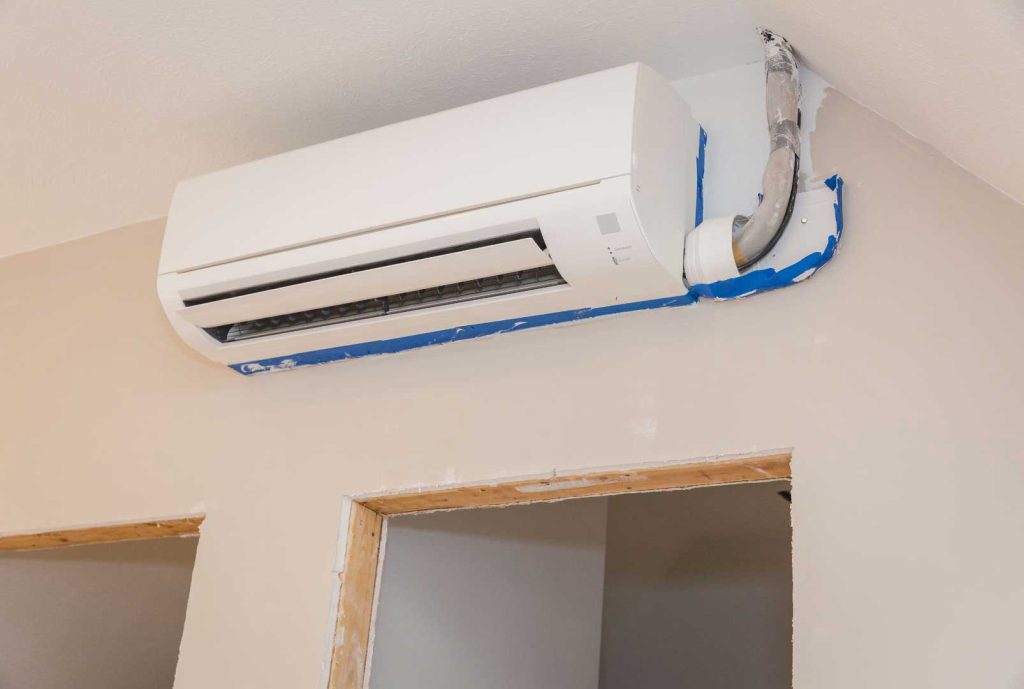 Wall-mounted mini-split air conditioner in a room under renovation.