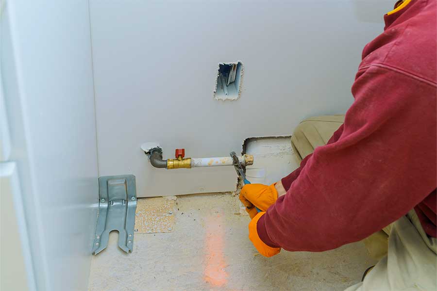 Technician in orange gloves working on a gas pipe connection
