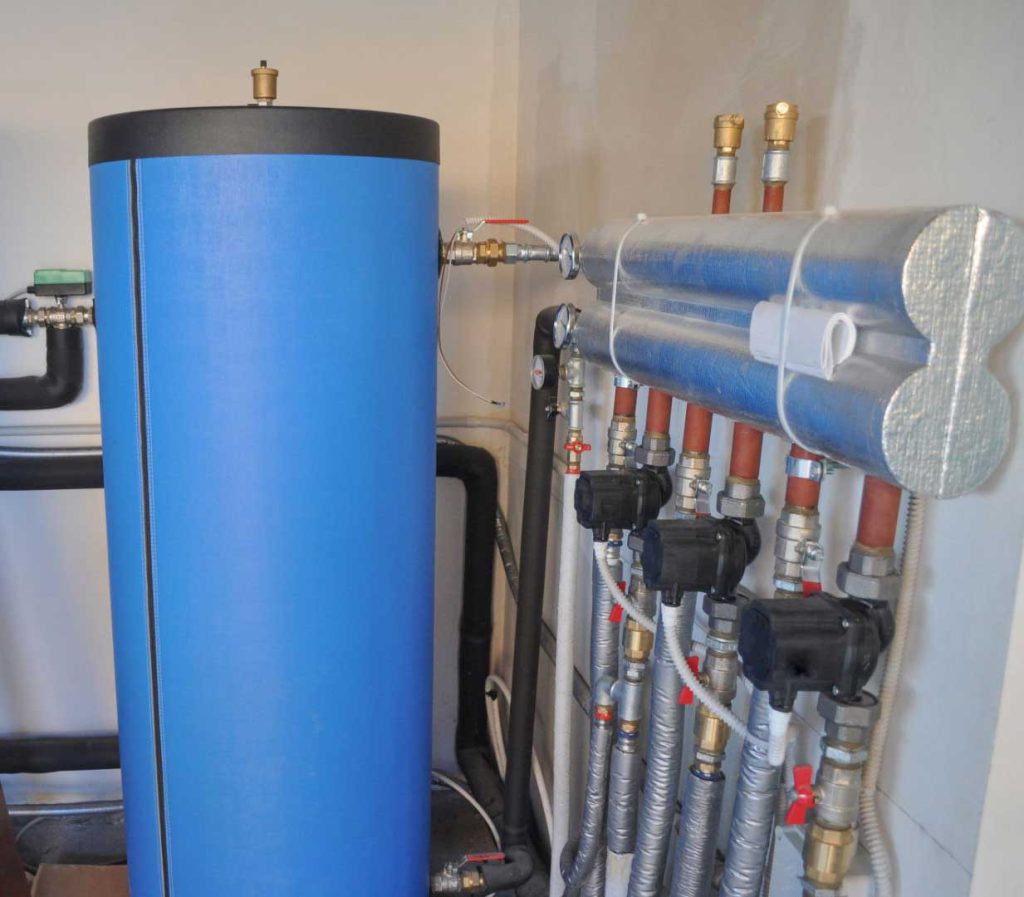 Blue insulated thermal storage tank with connected heating system pipes and valves.