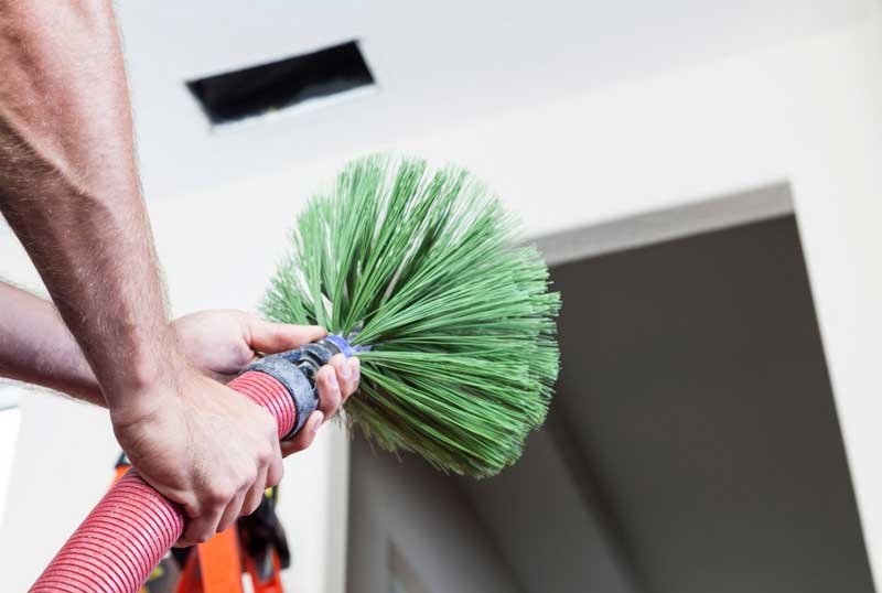 Close-up of a duct cleaning tool with stiff bristles used for removing debris from ventilation systems
