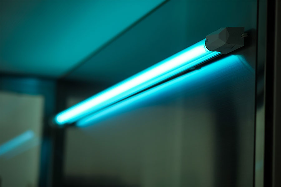 Glowing blue UV light tube mounted on a reflective surface