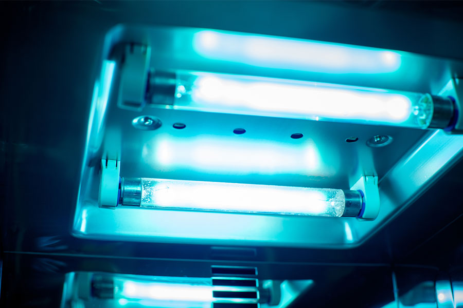 Two glowing UV light tubes installed in a reflective chamber.