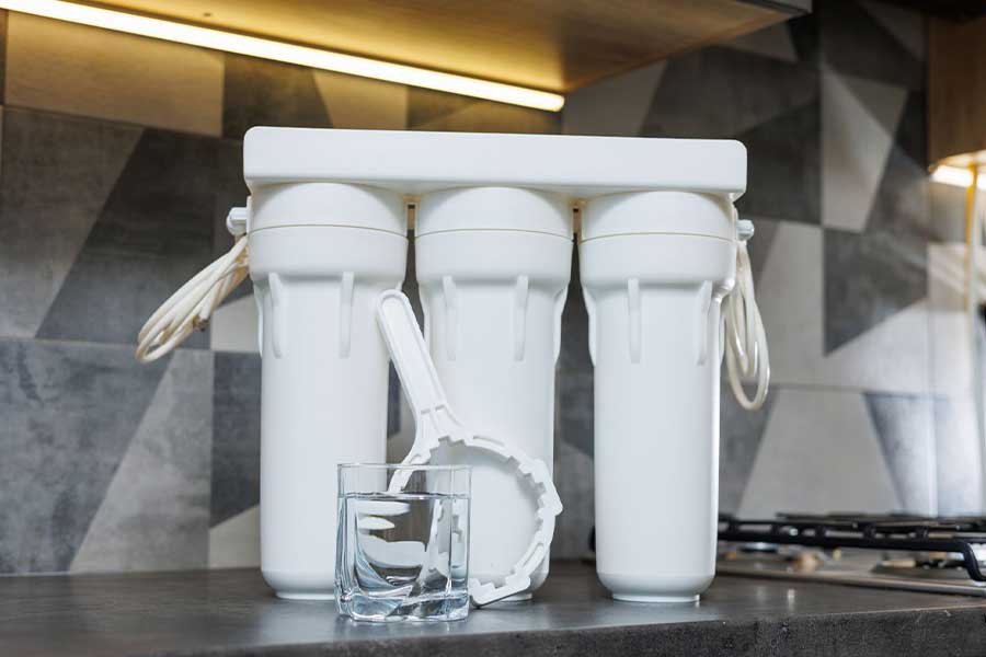 Triple-stage water filter system with a glass of clean water