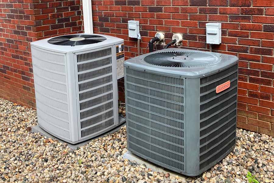 Two AC units installed outside a brick house