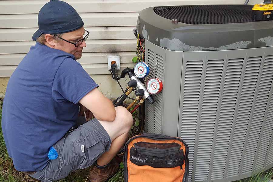 A technician is servicing an AC unit outside a home.